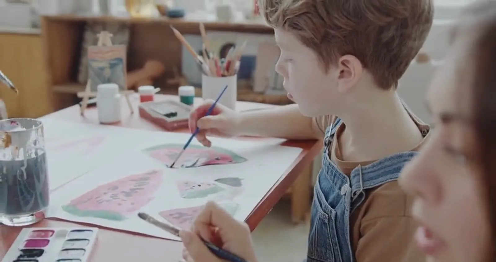 A young student painting watercolours at the art-class table