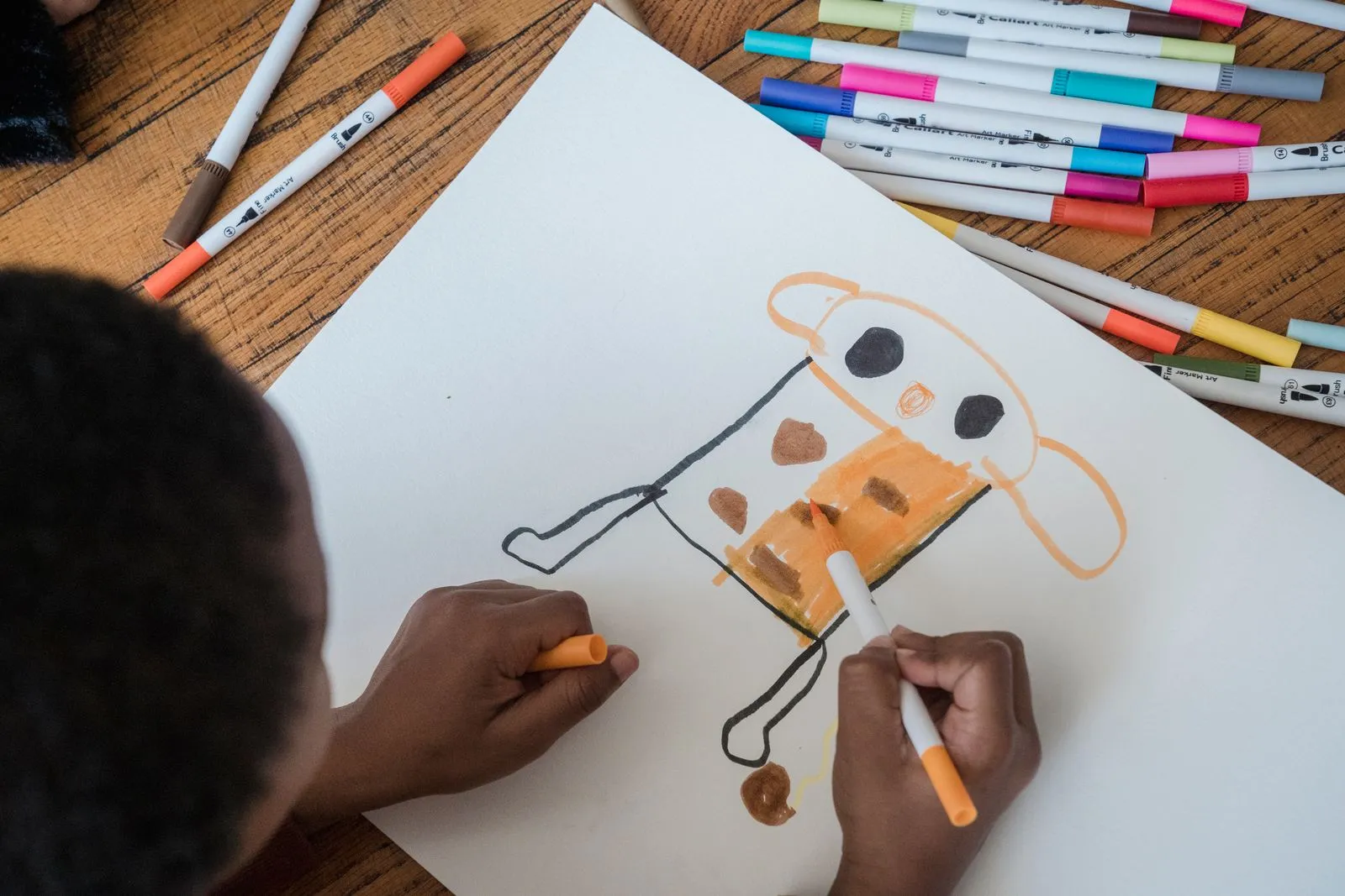 A child drawing a cartoon character with colourful markers
