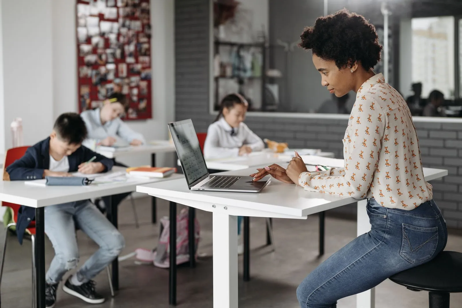 A teacher handling class admin on her laptop while students work