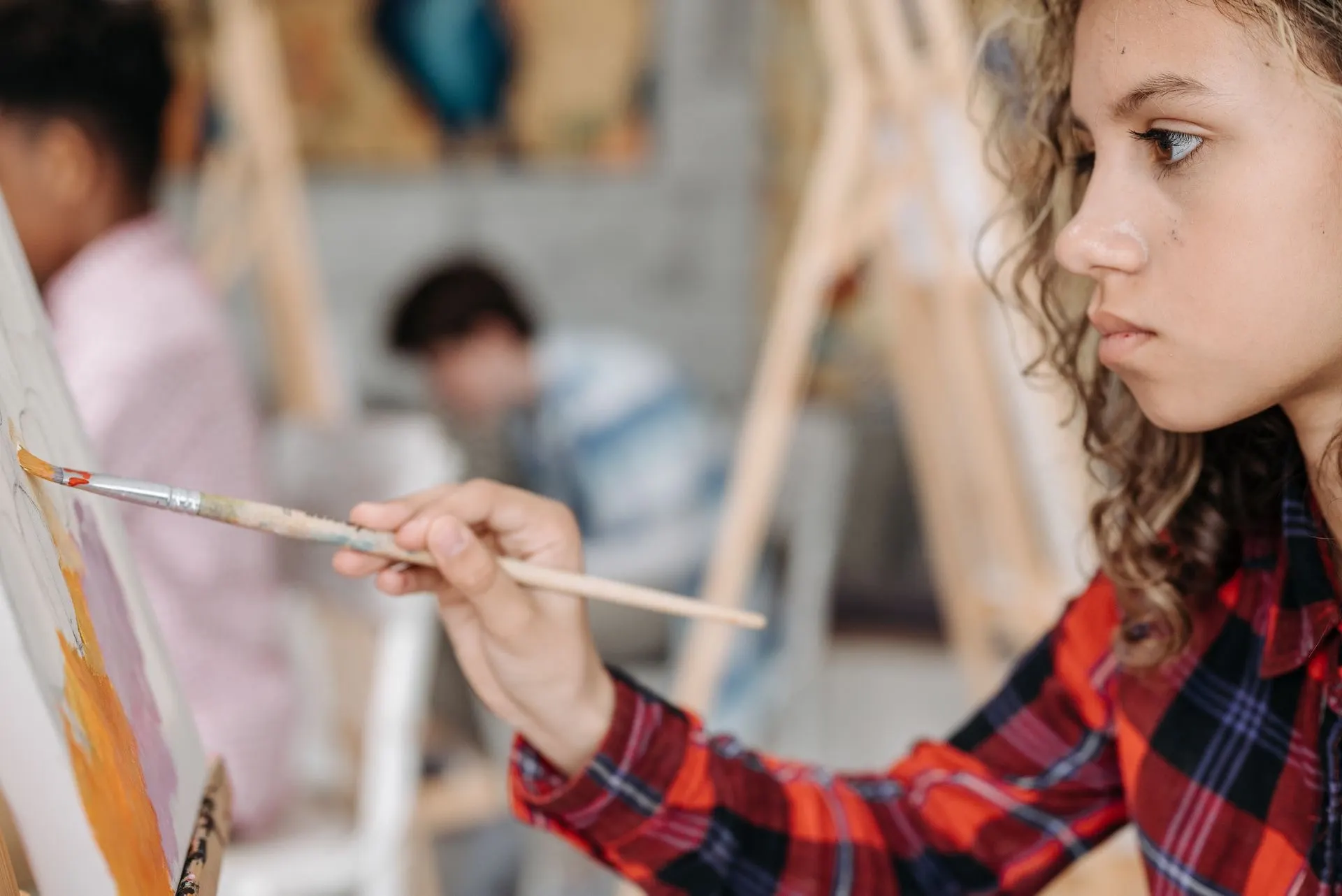 A child's hands covered in paint while working on a canvas